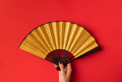 yellow hand-held fan against red bckground