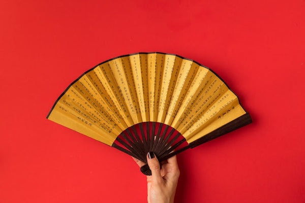 yellow hand-held fan against red bckground